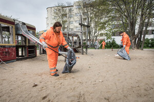Einsatzkräfte der BSR sammeln Abfall von einer Sandfläche