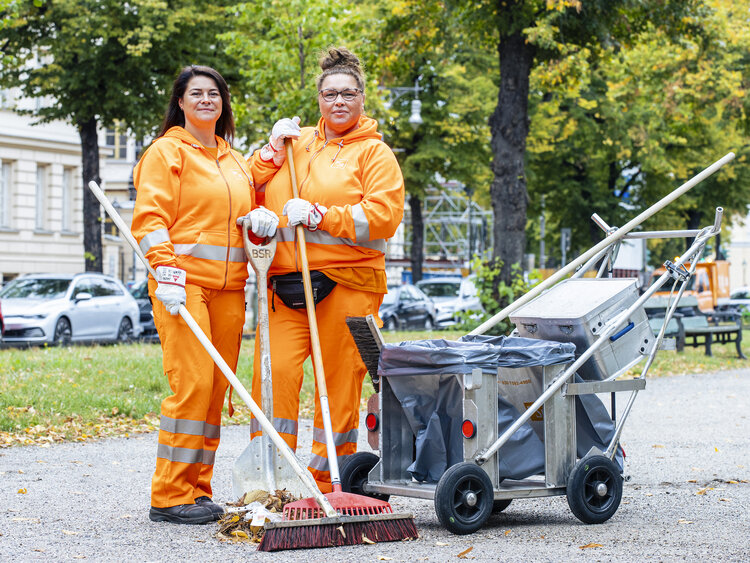 BSR-Mitarbeiterinnen in orangefarbener Kleidung aus der Straßenreinigung mit Besen in der Hand